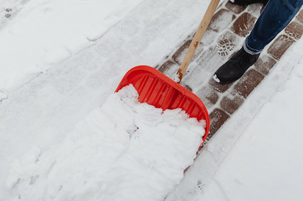 Person Shoveling Snow On A Path As A Part Of Snow Plow Services in Idaho Falls